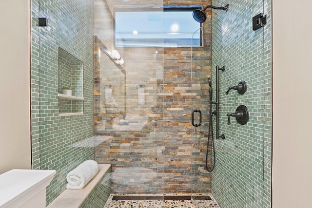 bathroom with a shower with shower door and toilet