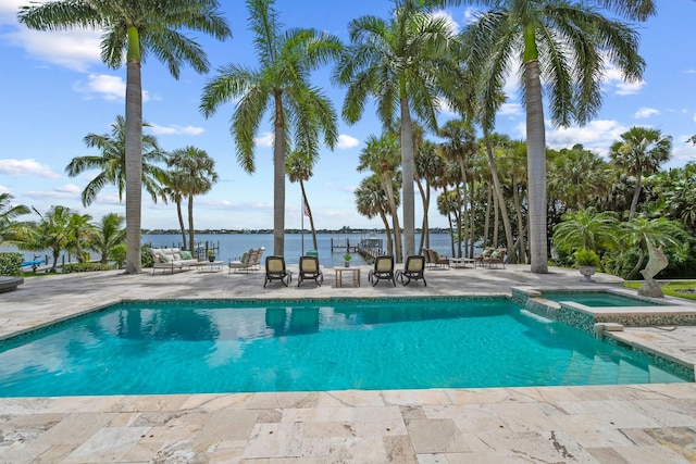 view of pool with an in ground hot tub, a water view, and a patio