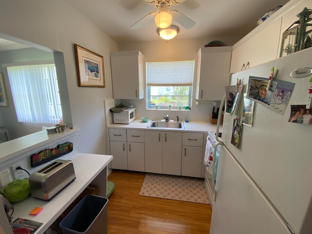 kitchen with white appliances, ceiling fan, sink, white cabinets, and light hardwood / wood-style floors