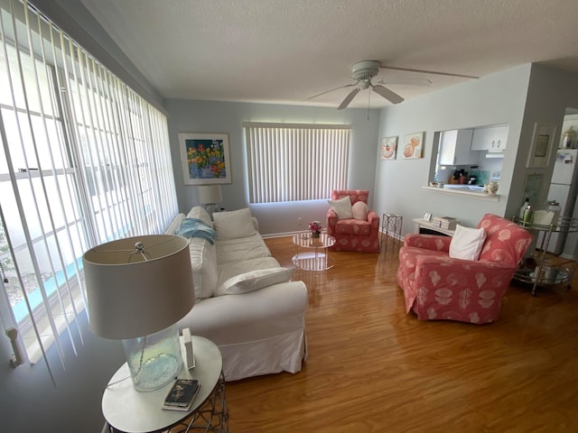 living room featuring ceiling fan, hardwood / wood-style floors, and a textured ceiling