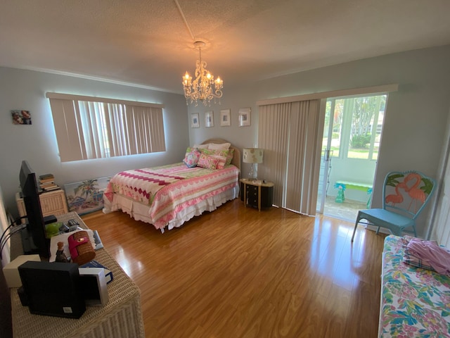 bedroom with a chandelier, wood-type flooring, a textured ceiling, and ornamental molding