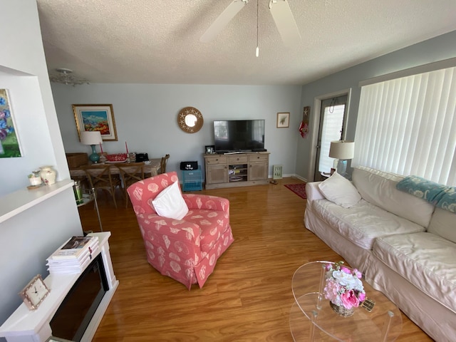 living room with a textured ceiling, hardwood / wood-style flooring, and ceiling fan