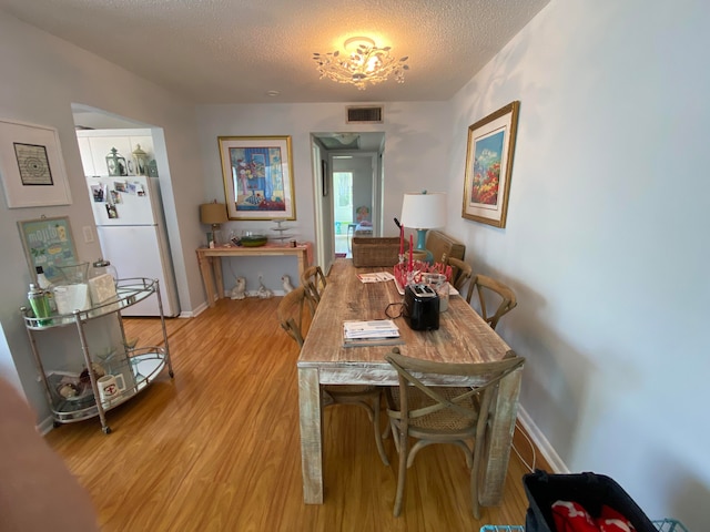 dining space with a textured ceiling and light wood-type flooring