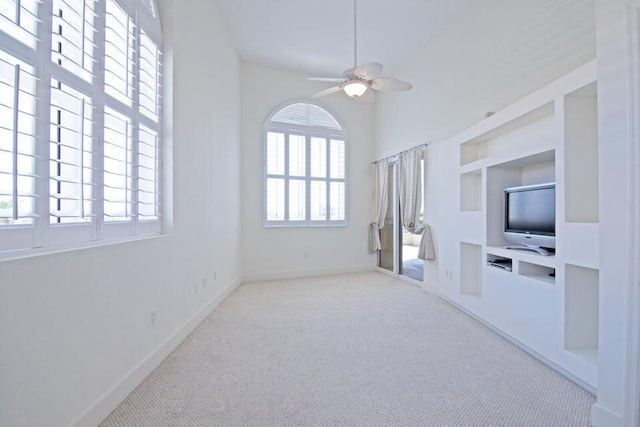 unfurnished living room with built in features, ceiling fan, and light colored carpet