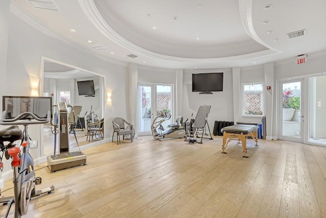 workout room with light hardwood / wood-style flooring, a raised ceiling, and crown molding