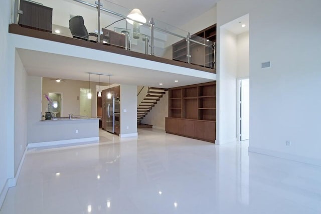 unfurnished living room featuring a towering ceiling and sink