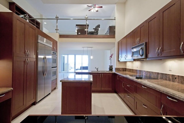 kitchen featuring appliances with stainless steel finishes, kitchen peninsula, stone countertops, sink, and ceiling fan