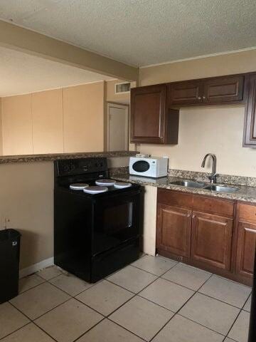 kitchen with stone countertops, sink, electric range, and light tile flooring