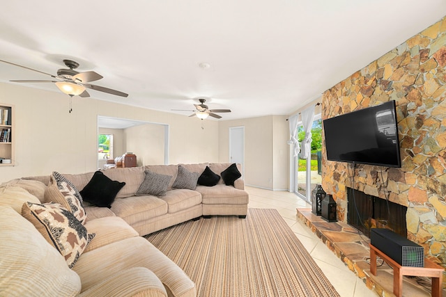 living room with a stone fireplace, ceiling fan, and light tile floors