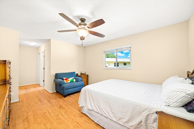 bedroom with ceiling fan, light hardwood / wood-style floors, and a textured ceiling