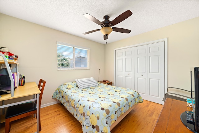 bedroom with ceiling fan, a closet, a textured ceiling, and wood-type flooring