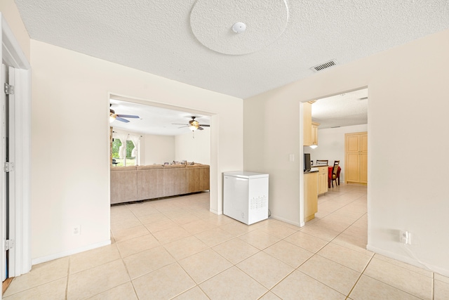 tiled empty room featuring ceiling fan and a textured ceiling