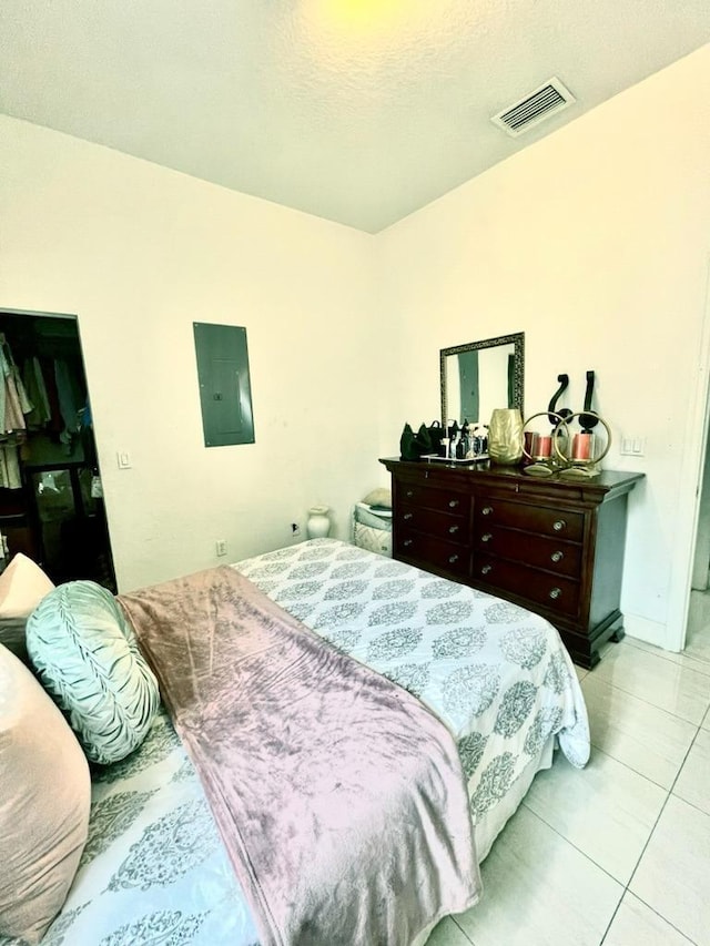 tiled bedroom with a textured ceiling and electric panel