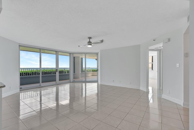 empty room with a textured ceiling, light tile patterned flooring, and floor to ceiling windows