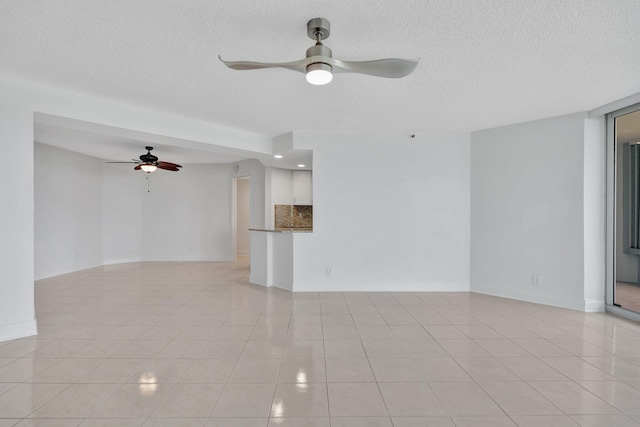 unfurnished living room featuring ceiling fan, light tile patterned flooring, and a textured ceiling