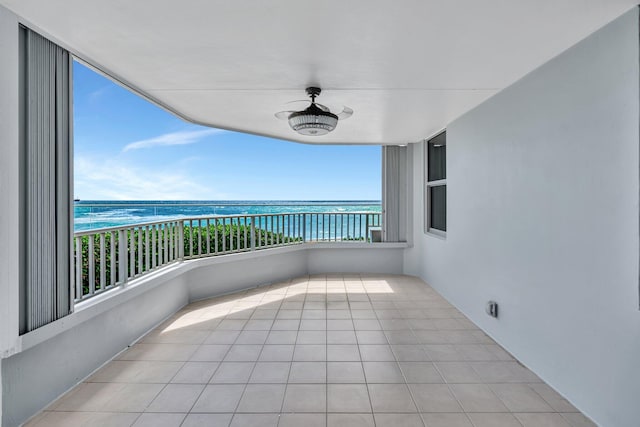 balcony featuring ceiling fan, a water view, and a view of the beach