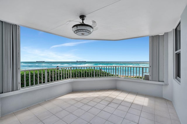 balcony featuring ceiling fan, a water view, and a beach view