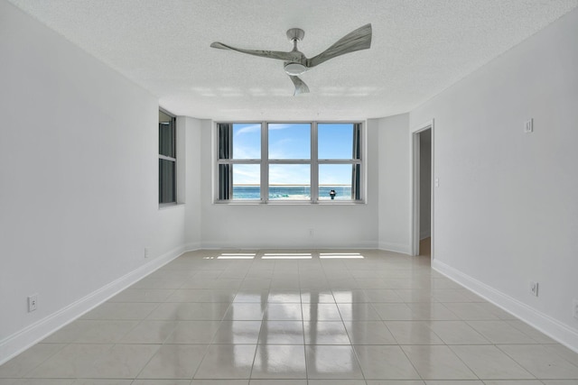 tiled spare room featuring a textured ceiling and ceiling fan