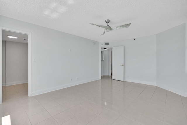 spare room with a textured ceiling, ceiling fan, and light tile patterned floors