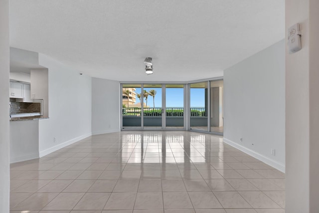 tiled empty room with a textured ceiling and a wall of windows