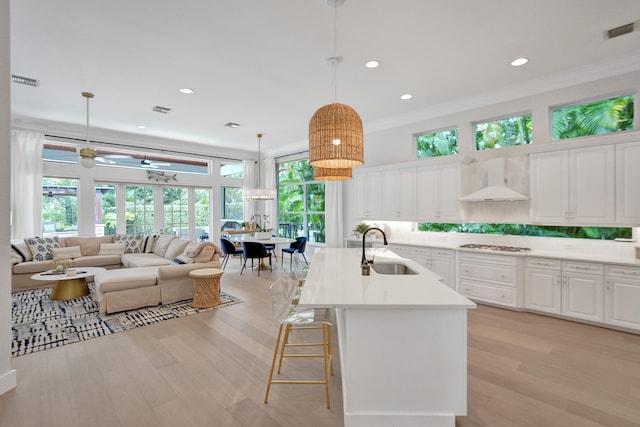 kitchen featuring a wealth of natural light, hanging light fixtures, sink, and white cabinets