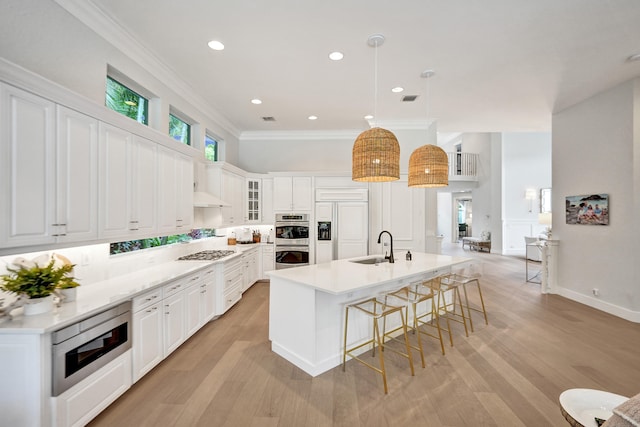 kitchen with light hardwood / wood-style floors, decorative light fixtures, built in appliances, and white cabinetry