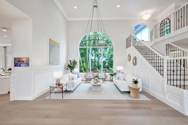 living room featuring a high ceiling, light wood-type flooring, and ornamental molding