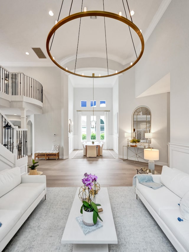 living room with a towering ceiling, wood-type flooring, and crown molding