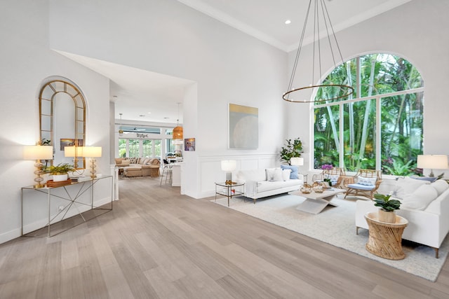 living room with light hardwood / wood-style flooring, a high ceiling, and a wealth of natural light