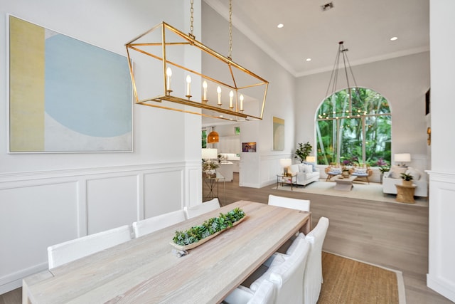 dining area with crown molding, a chandelier, a towering ceiling, and wood-type flooring