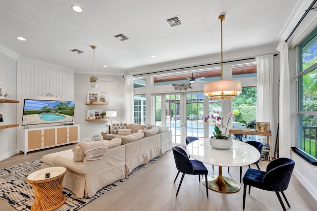 living room featuring french doors, ornamental molding, and light wood-type flooring