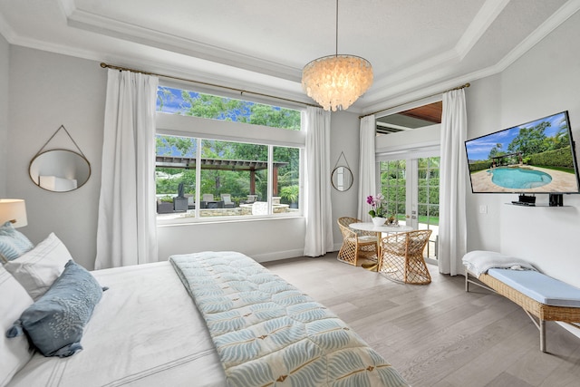 bedroom featuring light hardwood / wood-style floors, crown molding, a notable chandelier, and a tray ceiling