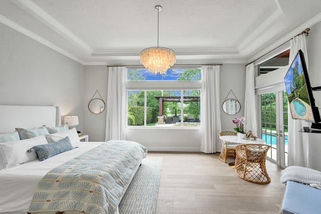 bedroom featuring a notable chandelier, a tray ceiling, light hardwood / wood-style flooring, and multiple windows