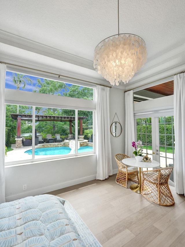 bedroom featuring french doors, light wood-type flooring, multiple windows, and a textured ceiling