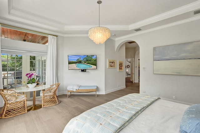 bedroom featuring ornamental molding, an inviting chandelier, a raised ceiling, and hardwood / wood-style floors