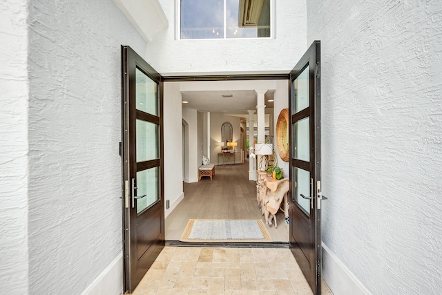 hall featuring hardwood / wood-style floors, decorative columns, and french doors