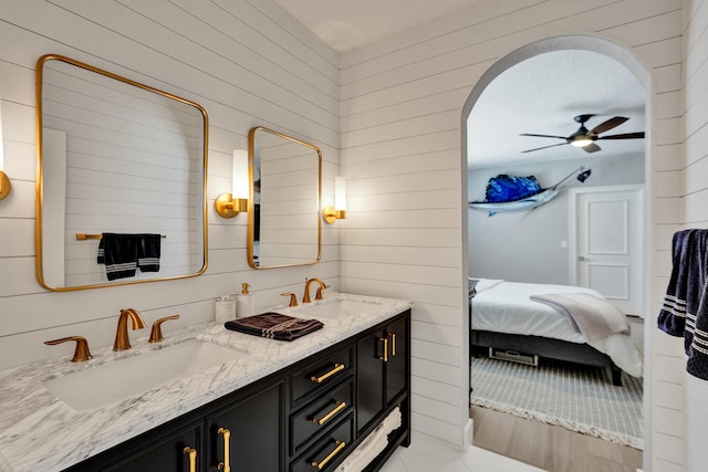 bathroom featuring ceiling fan, vanity, wooden walls, and tile patterned floors