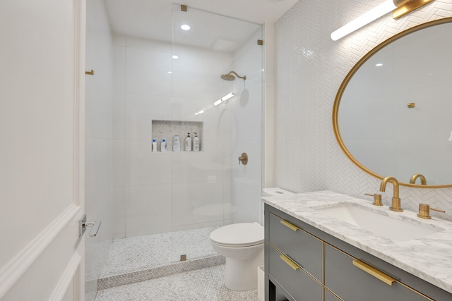 bathroom with tiled shower, vanity, and toilet