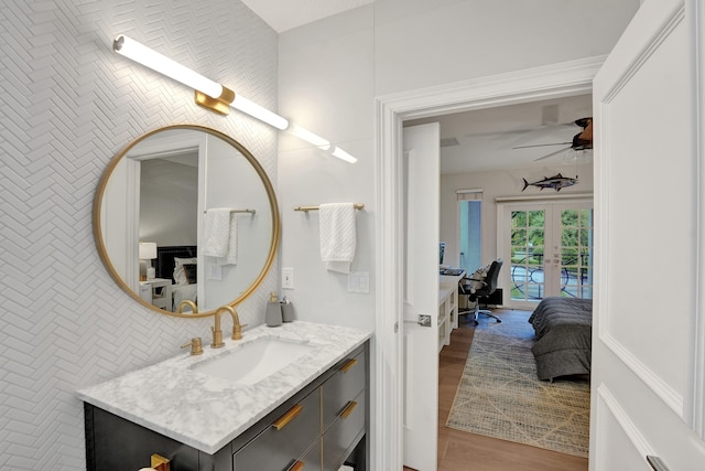 bathroom featuring ceiling fan, vanity, french doors, hardwood / wood-style flooring, and tile walls