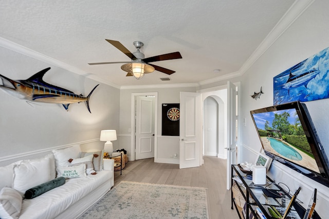 living room with ornamental molding, ceiling fan, a textured ceiling, and light hardwood / wood-style flooring