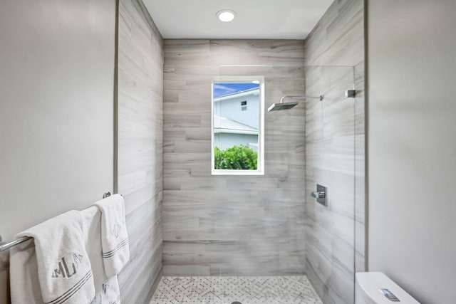 bathroom with tiled shower and toilet