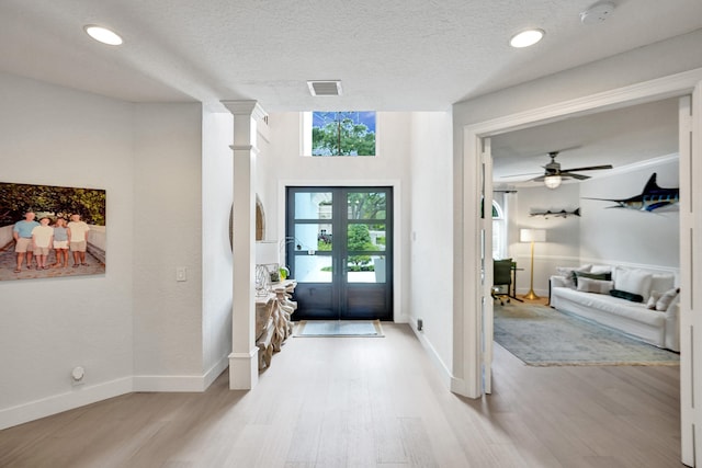 foyer with ceiling fan, french doors, light hardwood / wood-style flooring, and a textured ceiling