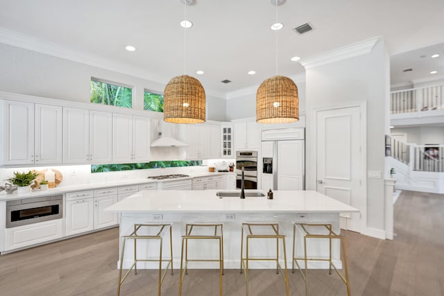 kitchen featuring sink, pendant lighting, white cabinetry, a center island with sink, and built in appliances