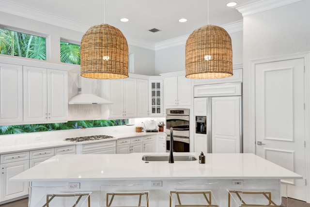 kitchen featuring a large island with sink, sink, white cabinets, appliances with stainless steel finishes, and a kitchen bar