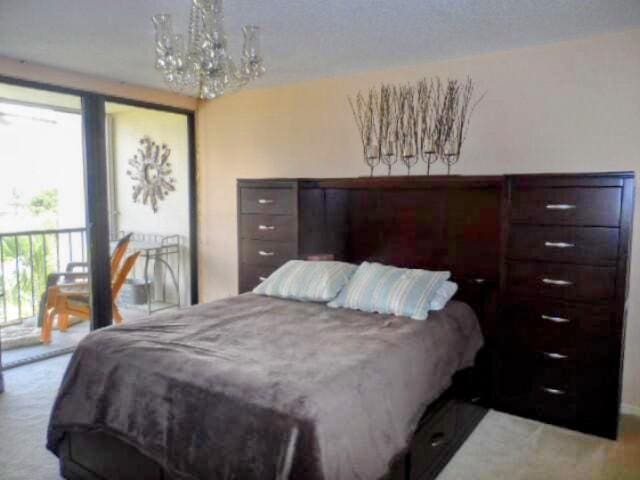 bedroom with a notable chandelier, carpet flooring, and access to outside