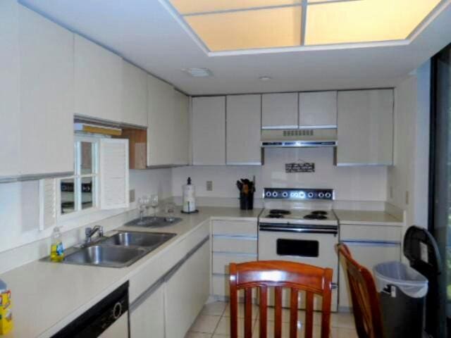 kitchen with white electric range, dishwasher, light tile flooring, sink, and white cabinets