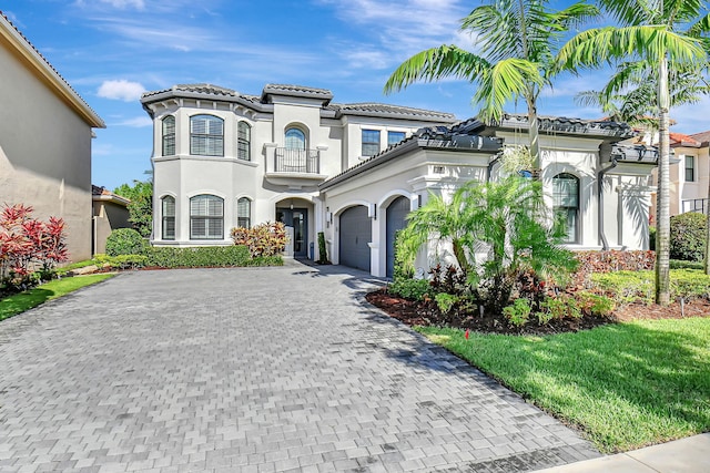 mediterranean / spanish-style home featuring a front yard, a garage, and a balcony