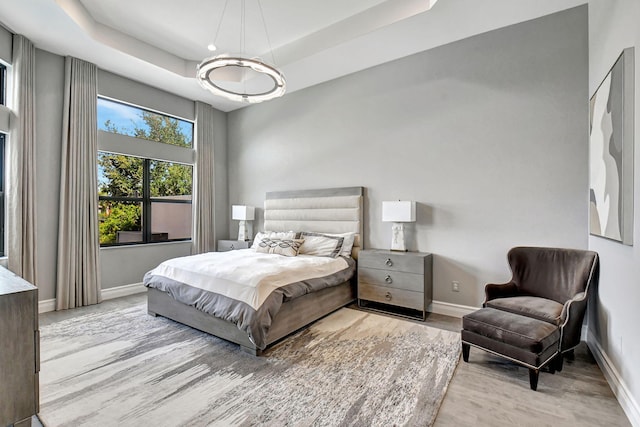 bedroom with light hardwood / wood-style flooring and a raised ceiling