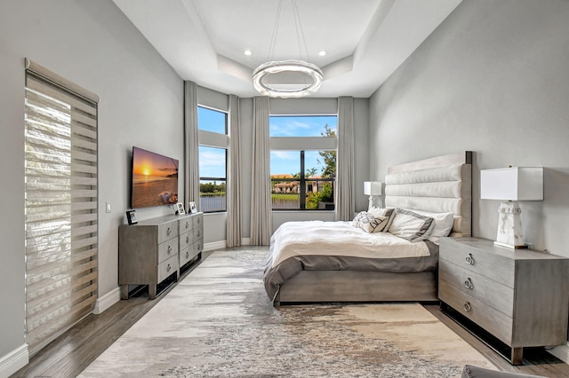 bedroom featuring a notable chandelier, a tray ceiling, and hardwood / wood-style floors