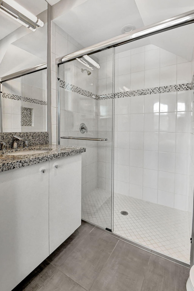 bathroom with tile floors, a shower with shower door, and vanity